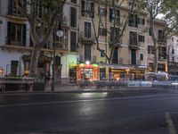 street view of people sitting at outdoor cafe tables, along road, in evening, with cars