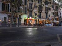 street view of people sitting at outdoor cafe tables, along road, in evening, with cars