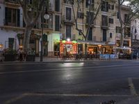 street view of people sitting at outdoor cafe tables, along road, in evening, with cars