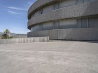 an empty concrete building with mountains in the background in daylight colors at the bottom of a parking lot