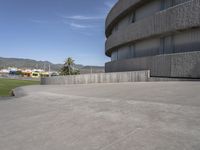 an empty concrete building with mountains in the background in daylight colors at the bottom of a parking lot