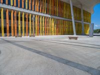 a concrete structure made into rows of orange and yellow poles are on a cement sidewalk