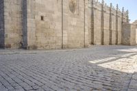 the old brick road between the large buildings is cobbled into stone blocks with an arch at the end