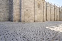 the old brick road between the large buildings is cobbled into stone blocks with an arch at the end