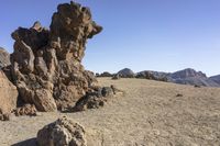 a large rock formation with rocks on a desert background, near mountains and blue sky