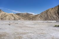 an empty dirt plain in the middle of the desert with a group of rocks and other vegetation