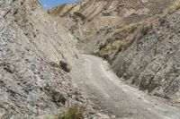 there is a large mountain with rocky walls and a gravel road leading through it to a cliff