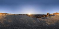 a dirt road with a mountain in the distance during sunset time, with sun casting bright