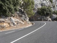 a motorcycle riding on a curvy road in a mountainous area near a mountain