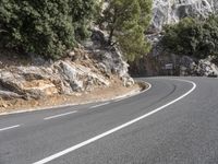 a motorcycle riding on a curvy road in a mountainous area near a mountain