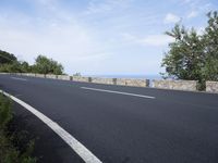 an empty road with a stone wall and blue sky behind it on a bright day