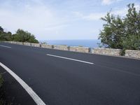an empty road with a stone wall and blue sky behind it on a bright day