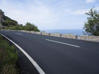 an empty road with a stone wall and blue sky behind it on a bright day