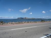 a road next to a wide body of water, and with rock - lined shoreline