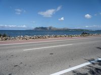 a road next to a wide body of water, and with rock - lined shoreline