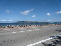 a road next to a wide body of water, and with rock - lined shoreline