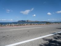 a road next to a wide body of water, and with rock - lined shoreline