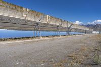 an old hydroelectric in the middle of a desert country near a body of water, with tall power lines, and a metal fence