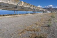 an old hydroelectric in the middle of a desert country near a body of water, with tall power lines, and a metal fence