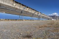 an old hydroelectric in the middle of a desert country near a body of water, with tall power lines, and a metal fence