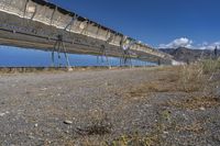 an old hydroelectric in the middle of a desert country near a body of water, with tall power lines, and a metal fence