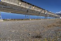 an old hydroelectric in the middle of a desert country near a body of water, with tall power lines, and a metal fence