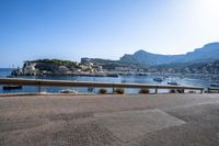 boats on the water, and a mountain in the distance from a railing to a street