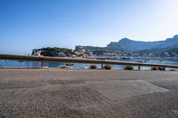 boats on the water, and a mountain in the distance from a railing to a street