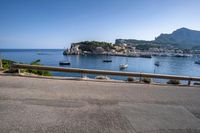 boats on the water, and a mountain in the distance from a railing to a street