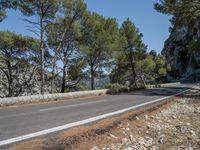 a road leading to an unpaved mountaintop with trees on both sides and rocks in the middle