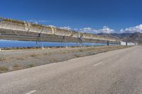 a man riding his motorcycle on the road near a bridge and solar panels across the road