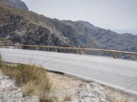 a motor bike is on a mountain side path over looking the mountains and ocean with water in the distance