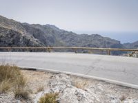 a motor bike is on a mountain side path over looking the mountains and ocean with water in the distance