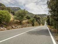 a motorcycle on a road going through some trees and mountains is seen here in the image