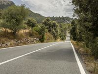 a motorcycle on a road going through some trees and mountains is seen here in the image