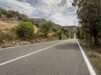 a motorcycle on a road going through some trees and mountains is seen here in the image