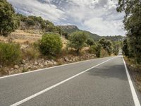 a motorcycle on a road going through some trees and mountains is seen here in the image