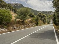 a motorcycle on a road going through some trees and mountains is seen here in the image