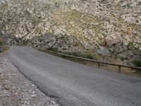a black motorcycle is parked by the side of a mountain road in the middle of nowhere