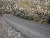 a black motorcycle is parked by the side of a mountain road in the middle of nowhere