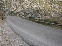 a black motorcycle is parked by the side of a mountain road in the middle of nowhere