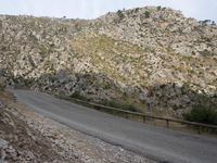 a black motorcycle is parked by the side of a mountain road in the middle of nowhere
