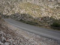 a black motorcycle is parked by the side of a mountain road in the middle of nowhere