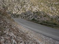 a black motorcycle is parked by the side of a mountain road in the middle of nowhere