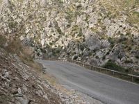 a black motorcycle is parked by the side of a mountain road in the middle of nowhere