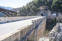 an empty roadway near the road leading to a cave on the mountain side with a tunnel and bridge