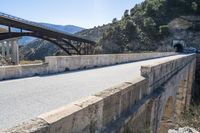 an empty roadway near the road leading to a cave on the mountain side with a tunnel and bridge