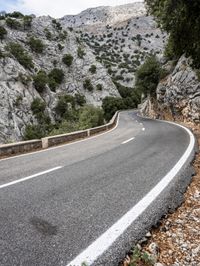 a mountain side with a curvy road on one side and a mountain on the other