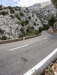 a mountain side with a curvy road on one side and a mountain on the other