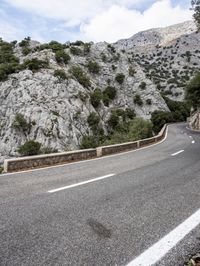 a mountain side with a curvy road on one side and a mountain on the other